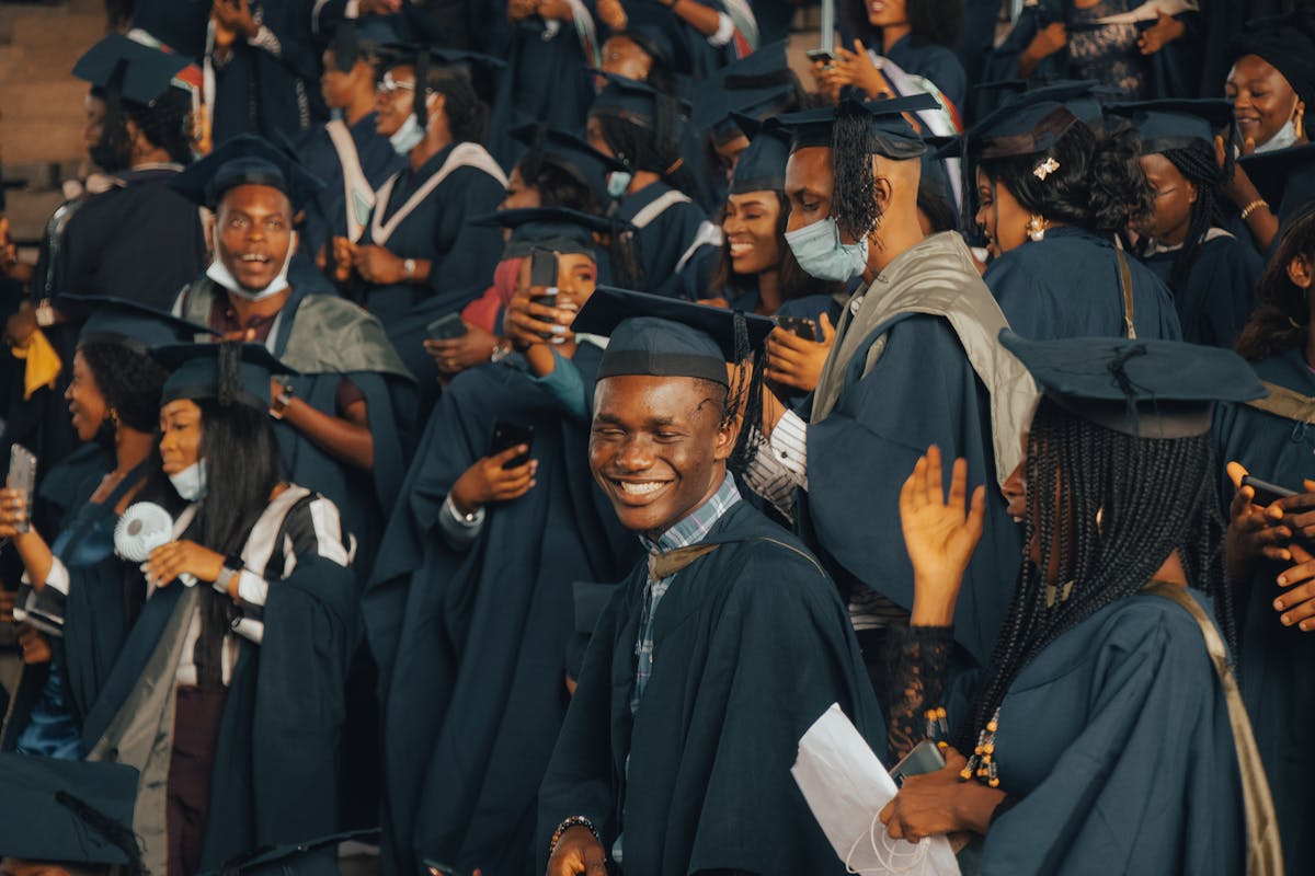 Nigerian university graduates in gowns celebrating outdoors